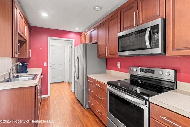 kitchen featuring a sink, light wood-type flooring, appliances with stainless steel finishes, and light countertops