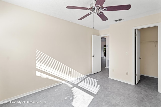 unfurnished bedroom featuring a closet, visible vents, a walk in closet, and baseboards