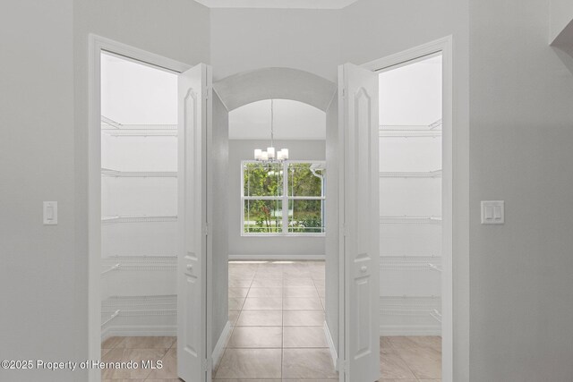 hallway with arched walkways and a notable chandelier