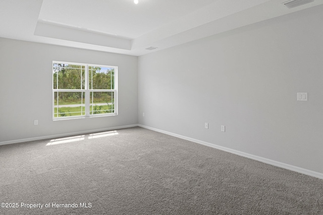 carpeted empty room featuring a raised ceiling, visible vents, and baseboards