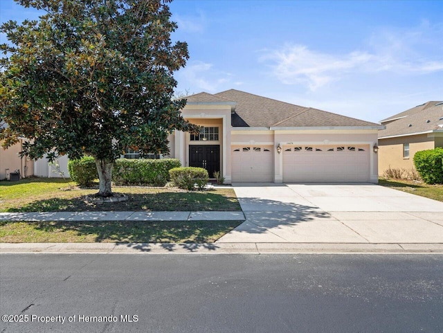 view of front facade featuring stucco siding, roof with shingles, concrete driveway, and an attached garage