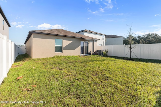 back of house featuring a fenced backyard, stucco siding, central AC, and a yard