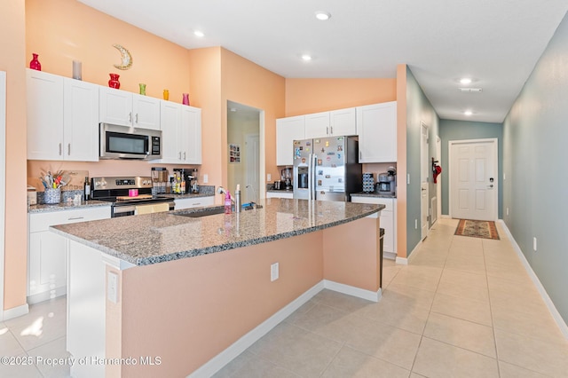 kitchen with a center island with sink, a sink, stainless steel appliances, white cabinets, and light tile patterned floors