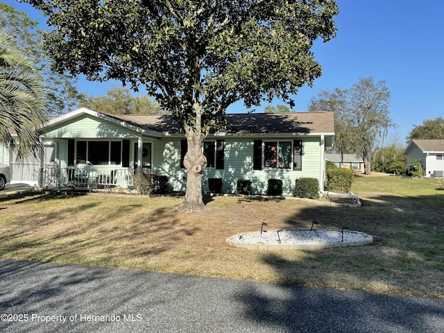 view of front facade featuring a front yard, covered porch, and roof with shingles