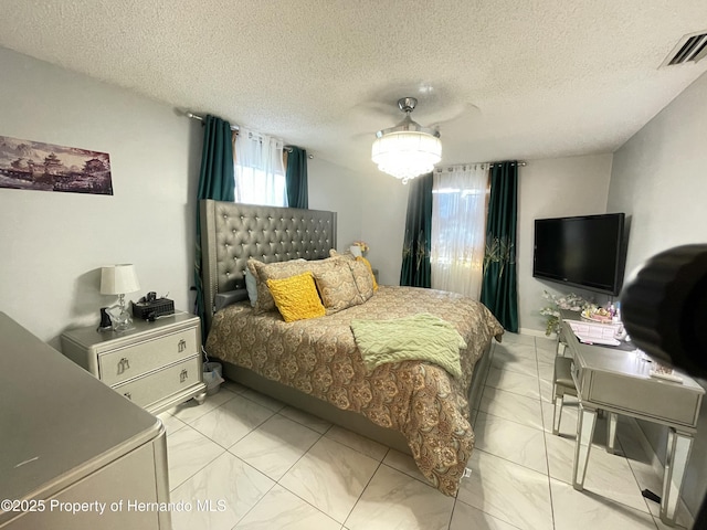 bedroom with a ceiling fan, visible vents, and a textured ceiling