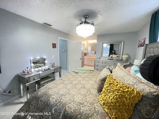 bedroom with visible vents, ensuite bathroom, and a textured ceiling