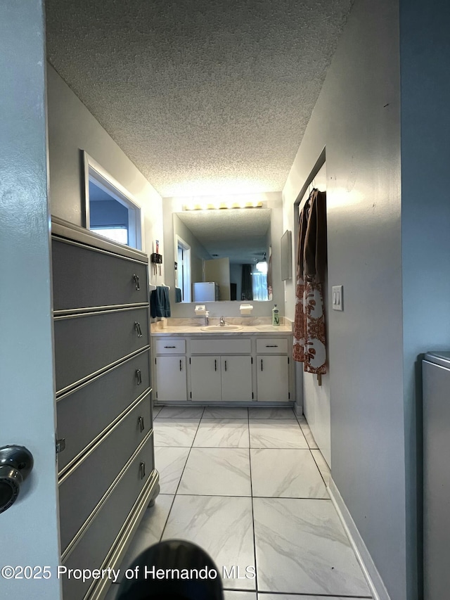 bathroom with vanity, baseboards, marble finish floor, and a textured ceiling