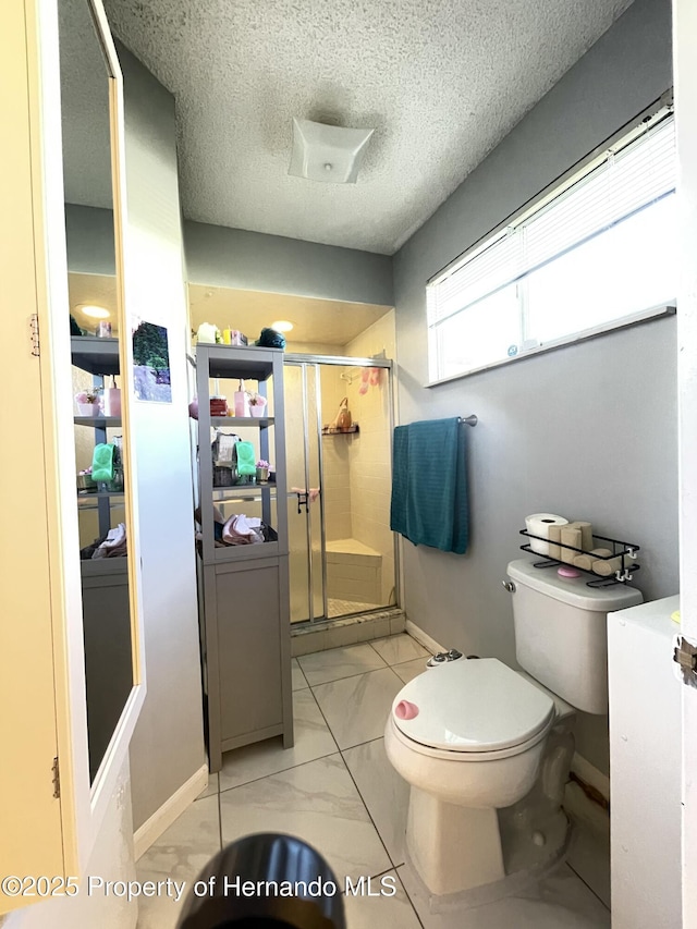 full bathroom featuring a shower stall, toilet, marble finish floor, and a textured ceiling