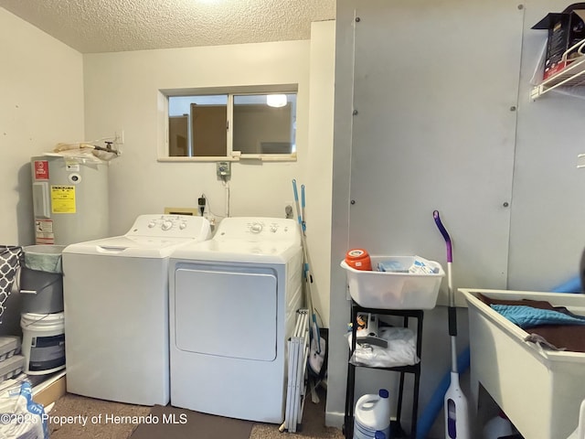 clothes washing area with washer and dryer, laundry area, water heater, and a textured ceiling