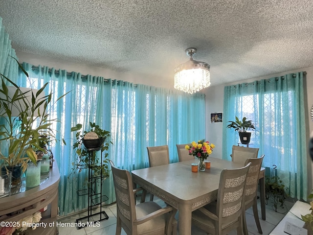 tiled dining space featuring a textured ceiling and a chandelier