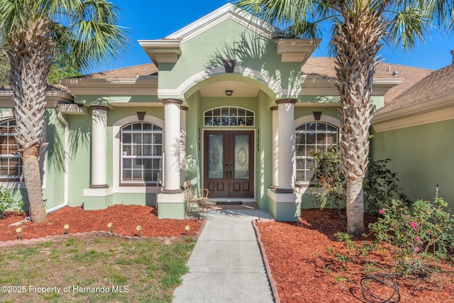 doorway to property with french doors, a shingled roof, and stucco siding