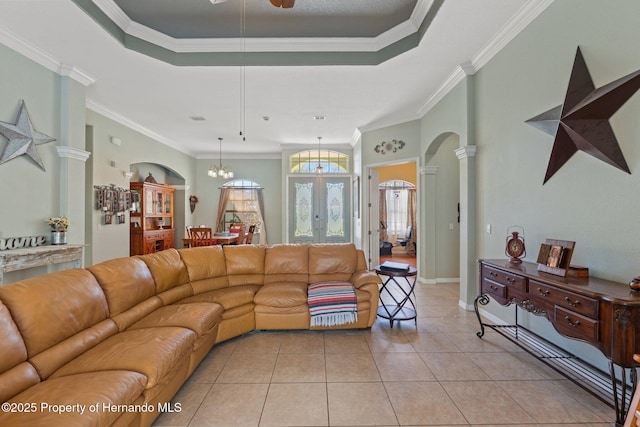 living room with arched walkways, a raised ceiling, light tile patterned flooring, and ornamental molding