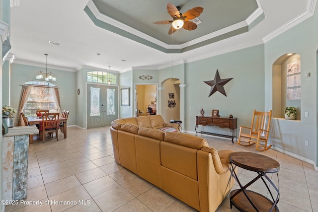 living area with visible vents, a tray ceiling, ornamental molding, ceiling fan with notable chandelier, and arched walkways