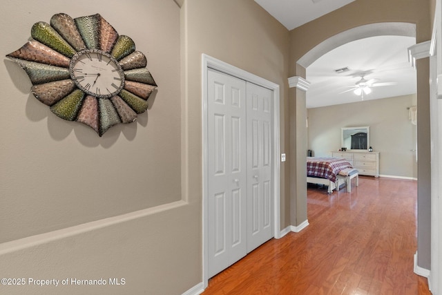 hallway featuring baseboards, arched walkways, and wood finished floors