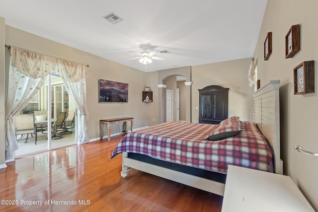 bedroom featuring visible vents, wood finished floors, arched walkways, baseboards, and access to exterior