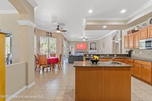 kitchen with a sink, stainless steel microwave, ceiling fan, and crown molding