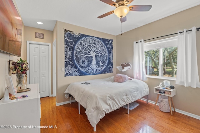 bedroom featuring baseboards, light wood finished floors, and ceiling fan