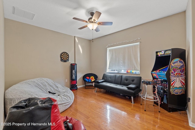 interior space featuring ceiling fan, visible vents, baseboards, and wood finished floors