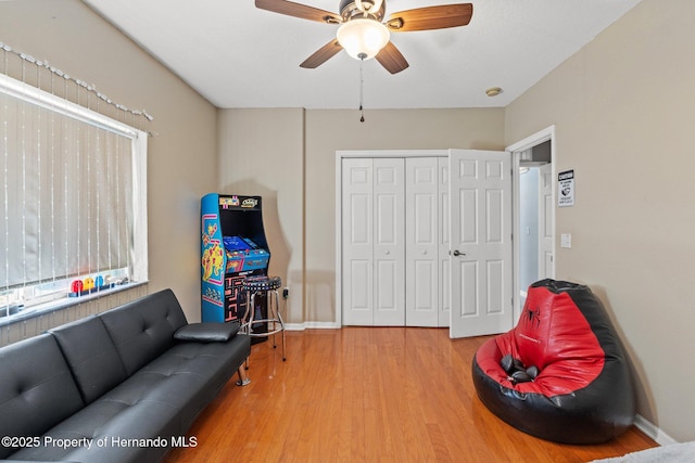 living area featuring baseboards, wood finished floors, and a ceiling fan