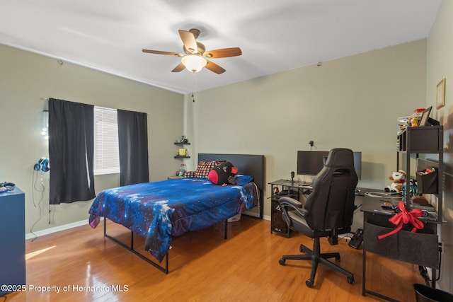 bedroom with a ceiling fan, wood finished floors, and baseboards