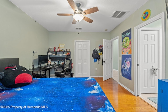 bedroom with visible vents, baseboards, ceiling fan, and wood finished floors