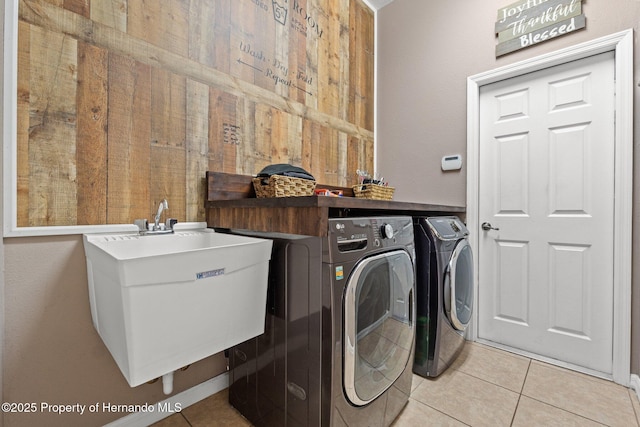 laundry area with light tile patterned floors, laundry area, independent washer and dryer, and a sink