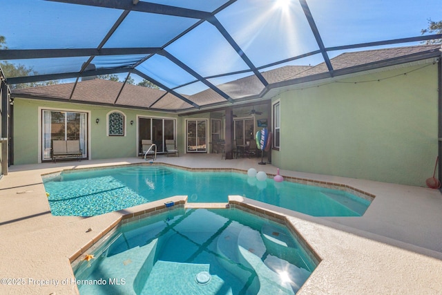 view of swimming pool featuring glass enclosure, a patio area, and a pool with connected hot tub