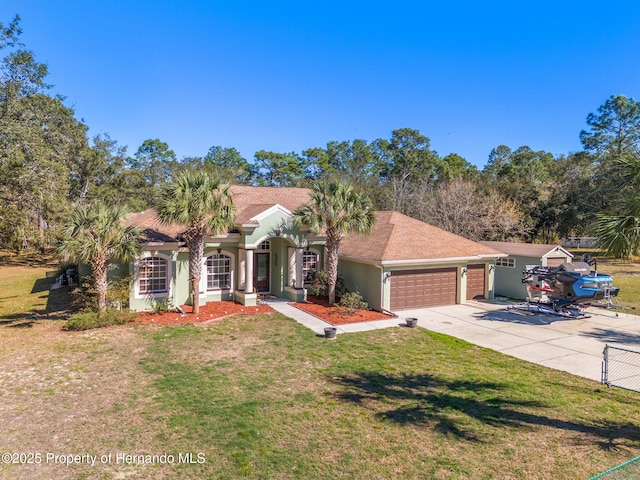 view of front of property featuring stucco siding, a front lawn, driveway, fence, and a garage