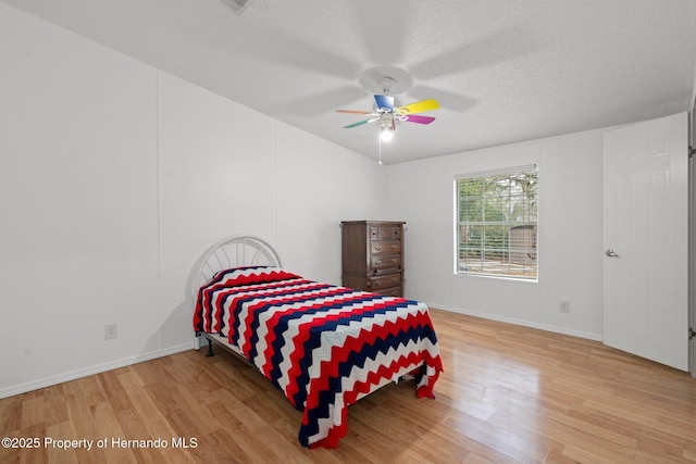 bedroom with baseboards, a textured ceiling, wood finished floors, and a ceiling fan