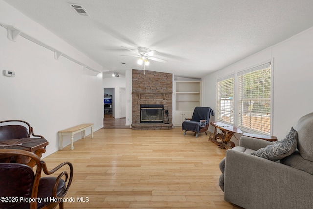 living area featuring a textured ceiling, lofted ceiling, light wood finished floors, and ceiling fan