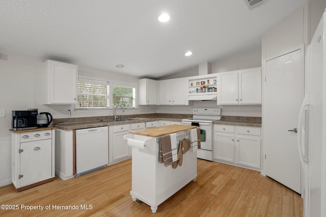 kitchen featuring light wood-style flooring, a sink, white cabinetry, white appliances, and vaulted ceiling