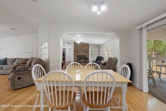 dining space featuring plenty of natural light, light wood-style flooring, a fireplace, and built in shelves
