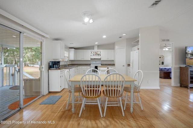 dining room with visible vents, lofted ceiling, and light wood-style floors