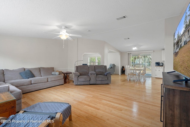living room featuring visible vents, arched walkways, a healthy amount of sunlight, and light wood-style flooring
