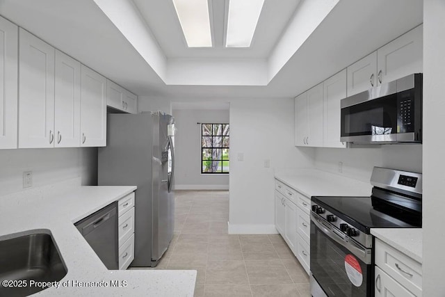 11080 Marquette St, Spring Hill, FL 34609 - kitchen featuring a tray ceiling, white cabinets, appliances with stainless steel finishes, and light tile patterned floors