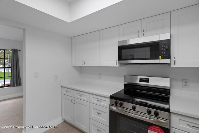 11080 Marquette St, Spring Hill, FL 34609 - kitchen featuring appliances with stainless steel finishes, light tile patterned floors, baseboards, and white cabinets