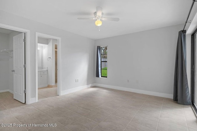 11080 Marquette St, Spring Hill, FL 34609 - unfurnished bedroom with ensuite bathroom, baseboards, a walk in closet, and light tile patterned flooring