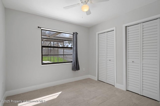 11080 Marquette St, Spring Hill, FL 34609 - unfurnished bedroom featuring tile patterned floors, baseboards, multiple closets, and ceiling fan