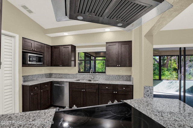 kitchen with stainless steel appliances, a sink, visible vents, range hood, and light stone countertops