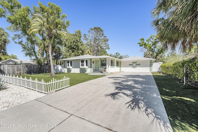 ranch-style home with a front lawn, driveway, a fenced front yard, and stucco siding