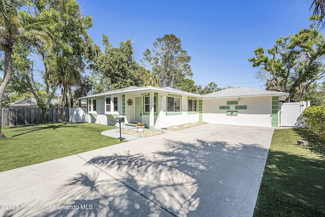 view of front of home featuring a front lawn, driveway, stucco siding, and fence