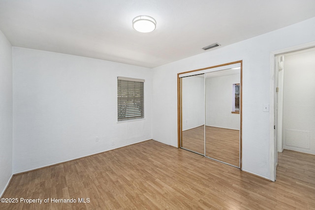 unfurnished bedroom with a closet, visible vents, and light wood-type flooring