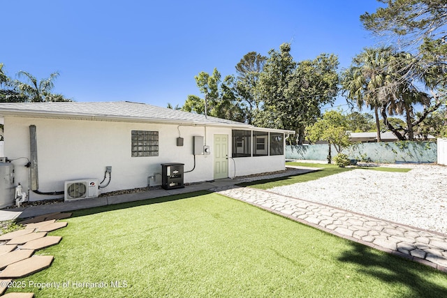 back of property featuring a sunroom, fence, stucco siding, and a yard