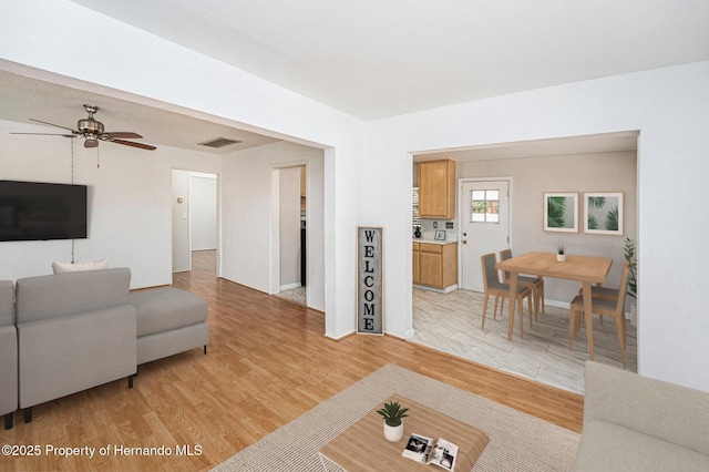living room featuring visible vents, light wood-style flooring, and ceiling fan