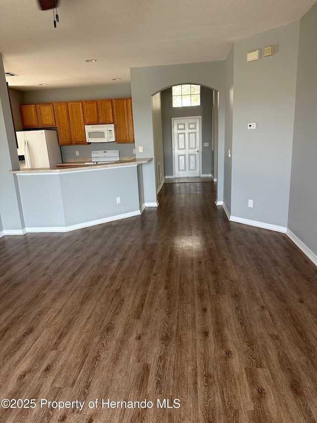8480 Southern Charm Cir, Brooksville, FL 34613 - kitchen featuring dark wood-style floors, brown cabinets, baseboards, white appliances, and arched walkways