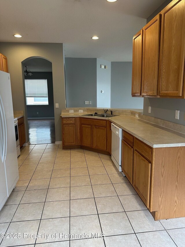 8480 Southern Charm Cir, Brooksville, FL 34613 - kitchen featuring light tile patterned flooring, a sink, brown cabinetry, and white appliances