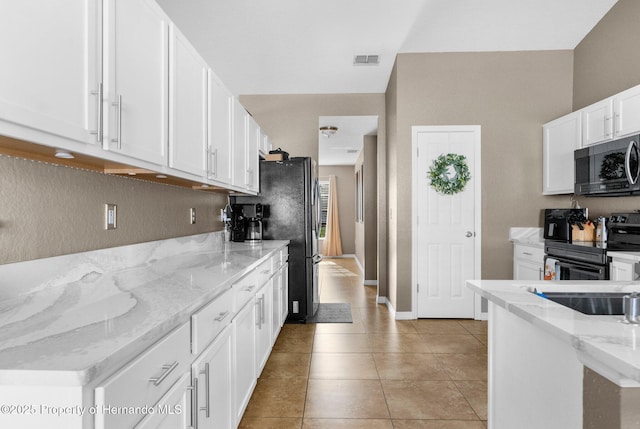 1018 Stratton Ave, Spring Hill, FL 34609 - kitchen with white cabinetry, light tile patterned flooring, visible vents, freestanding refrigerator, and black electric range