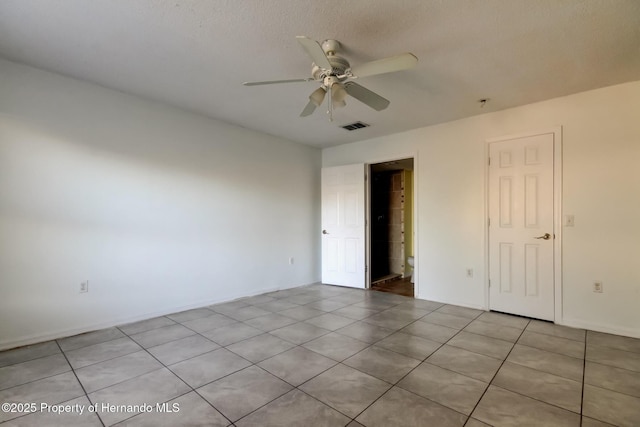 empty room featuring a ceiling fan, light tile patterned floors, and visible vents