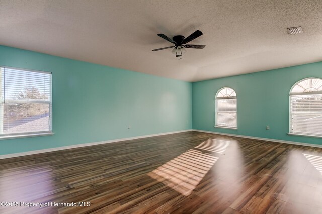 unfurnished room with dark wood finished floors, a textured ceiling, ceiling fan, and visible vents
