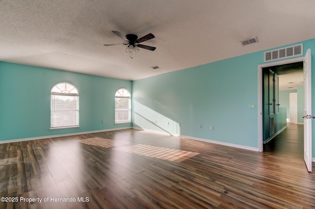 unfurnished room featuring visible vents, wood finished floors, and a ceiling fan